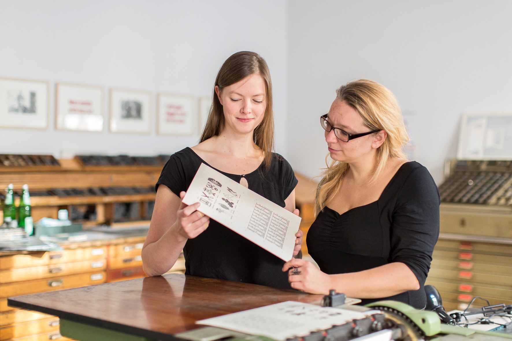 Annegret Rouél und Kathleen Hirschnitz mit dem Andruck der ersten KUNSTWIEGEKARTEN in der Druckwerkstatt des book art center halle. Foto: Matthias Ritzmann.