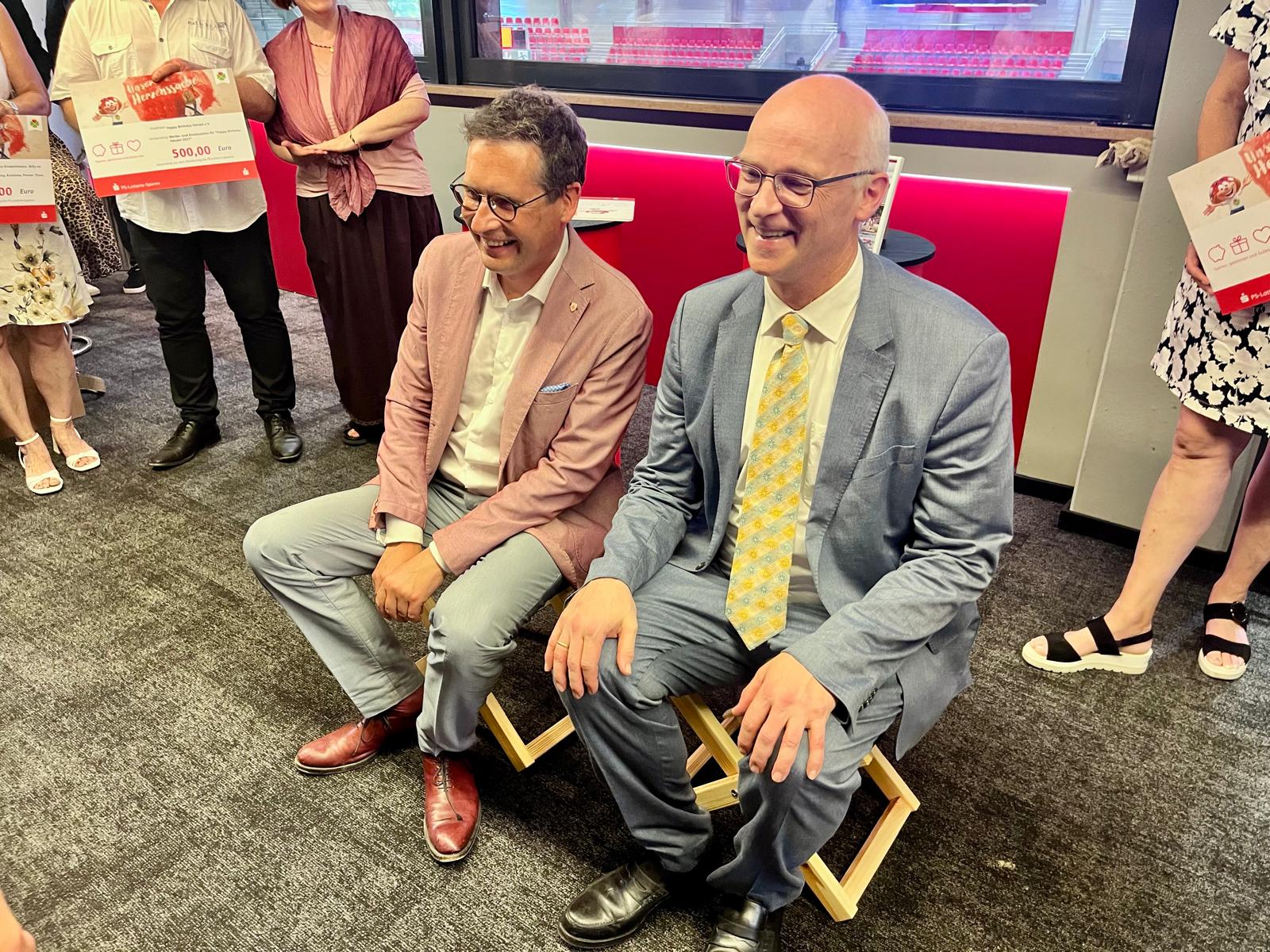 Dr. Jürgen Fox und Oberbürgermeister Alexander Vogt testen die Klapphocker des Fördervereins Zukunft Stadtbad Halle